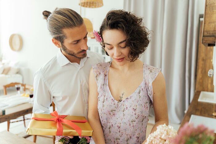Man giving a gift to a woman in a floral dress, illustrating bisexual dating dynamics and gender differences.