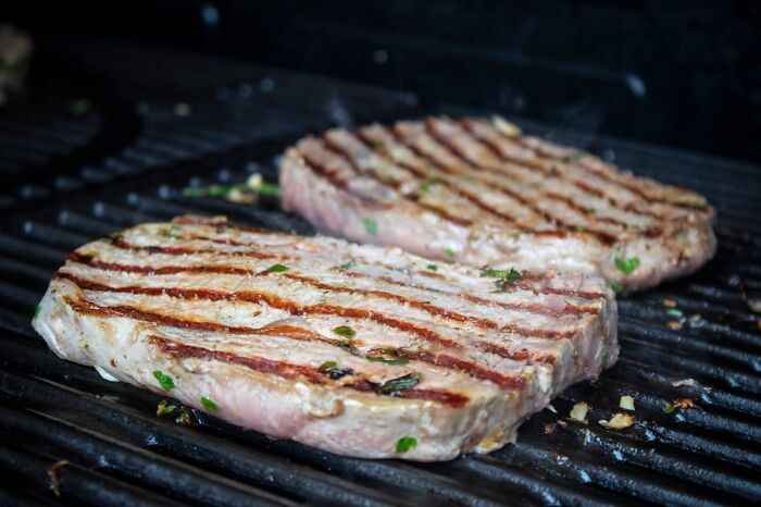 Grilled steaks on a barbecue grill, representing lifetime supply benefits.