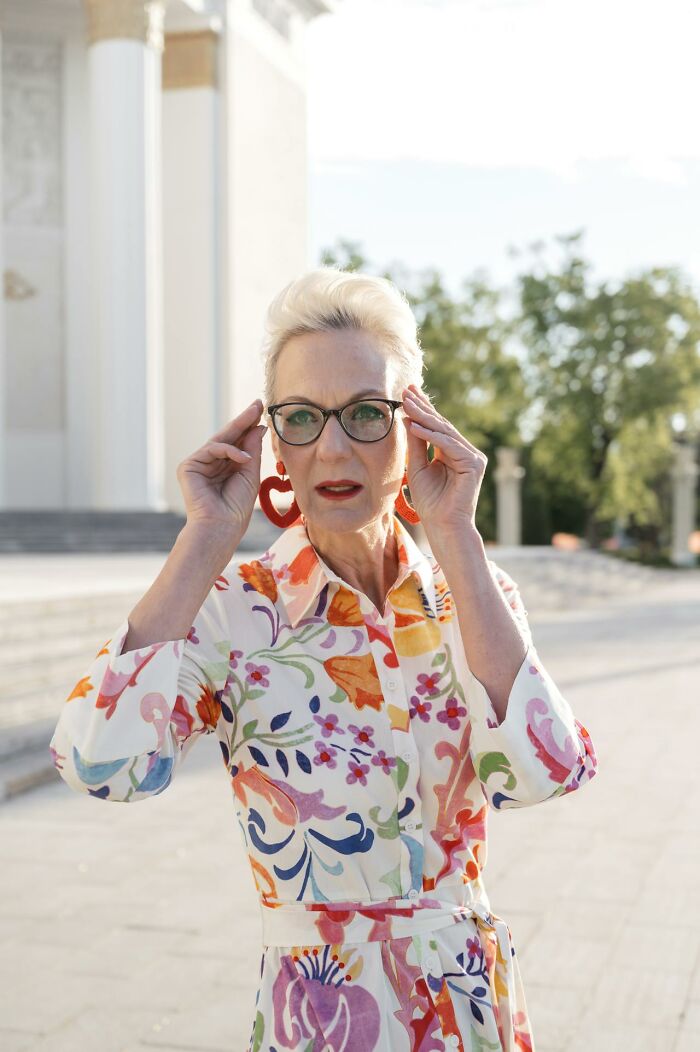 Woman in floral dress and glasses with red earrings at an outdoor wedding setting, symbolizing red flag moments.