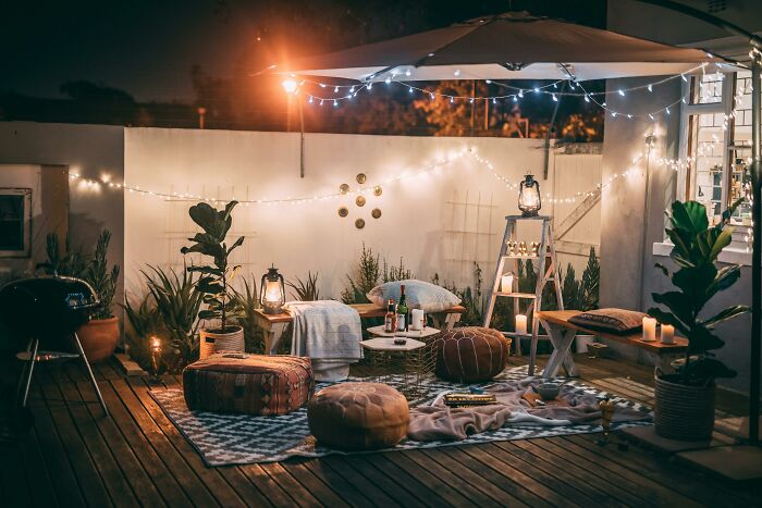 Cozy outdoor patio setting with cushions, candles, and string lights, creating a heartfelt and inviting atmosphere.