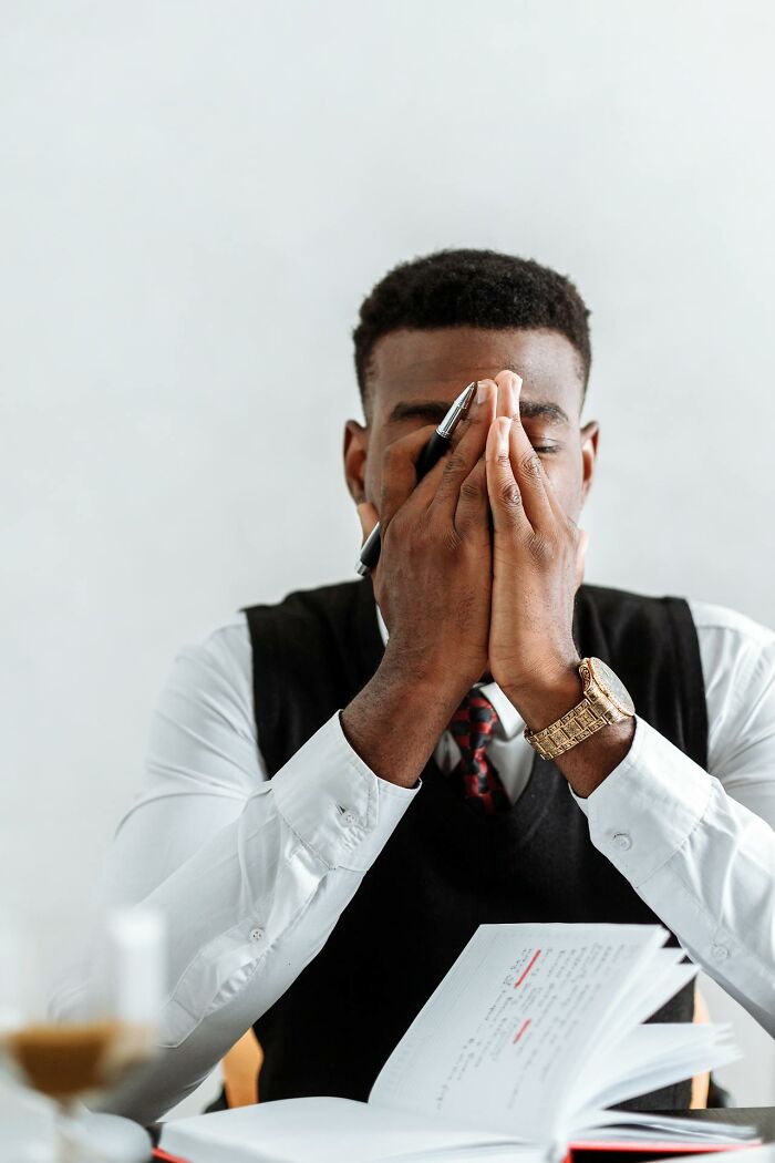 Distressed employee in office, holding head in hands, illustrating abrupt firing by boss.