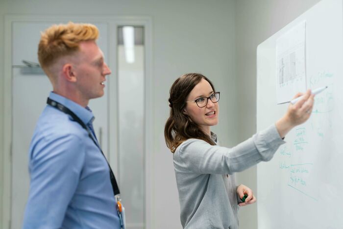Two people discussing a concept at a whiteboard, indicating intelligence and collaboration.