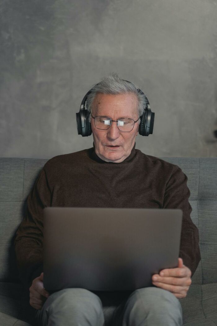 Elderly man with headphones using a laptop, possibly recalling ways to make money easily.