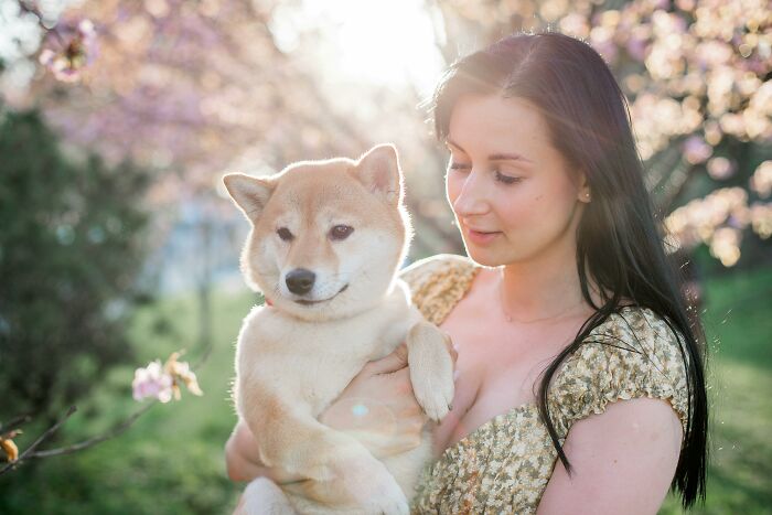 Woman holding a dog in a garden, showcasing hidden intelligence in her expression.