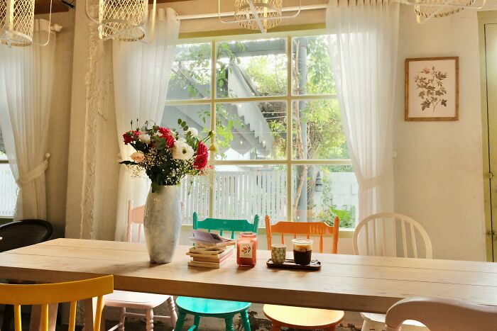 Comedor con sillas multicolores y mesa decorada, características de clase media.