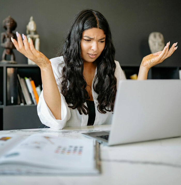 Woman at desk looking frustrated, reacting to worst bonus received at work on her laptop screen.