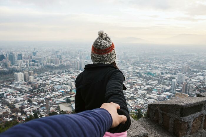 Person holding hands with another, overlooking city from a high point, representing bisexual dating experiences.