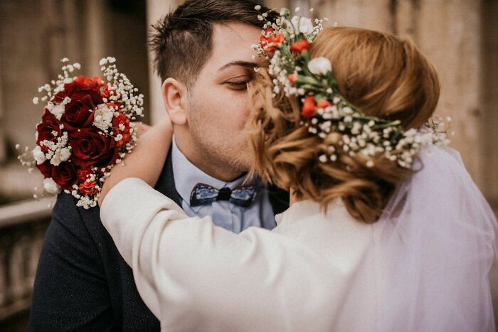 Bride and groom kissing, adorned with floral decorations during a wedding ceremony.
