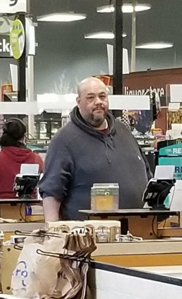 Person in a retail store, wearing a hoodie, at the checkout counter, conveying positivity and upliftment.