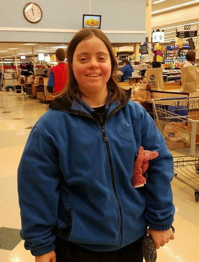 Smiling person in a blue jacket spreading positivity in a grocery store.