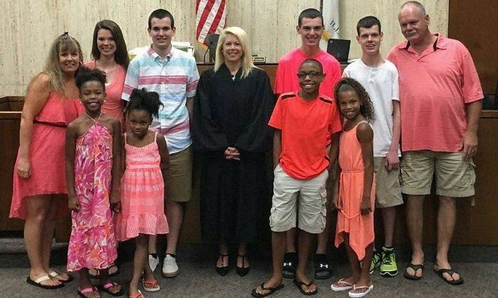 A happy group photo in front of a judge, wearing colorful outfits, capturing a positive and uplifting moment.