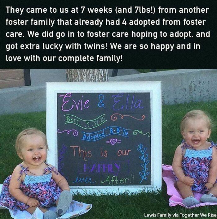 Twin babies sitting on grass beside a happy adoption announcement sign, embodying an uplifting and positive moment.