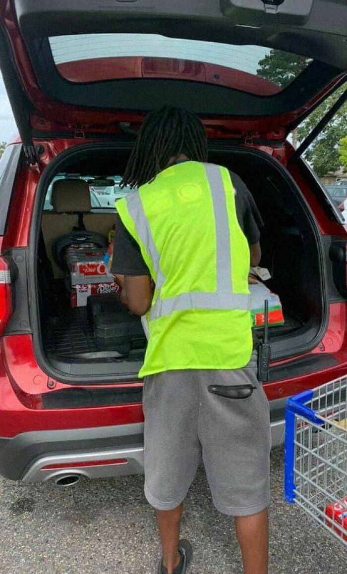 Person in a bright vest loading groceries into a red SUV, creating a positive and uplifting moment.