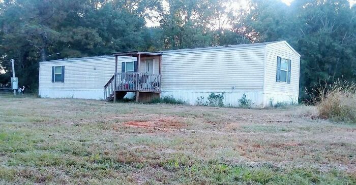 A mobile home in a grassy field with trees, capturing a serene and uplifting scene.