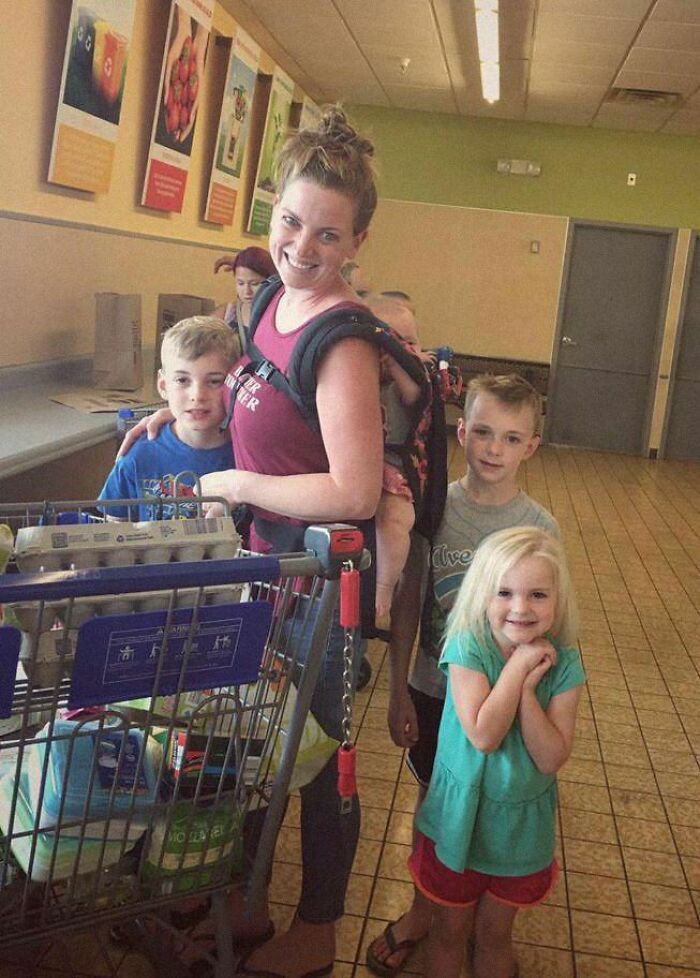 A smiling woman with kids at a grocery store checkout line, creating a positive and uplifting moment.