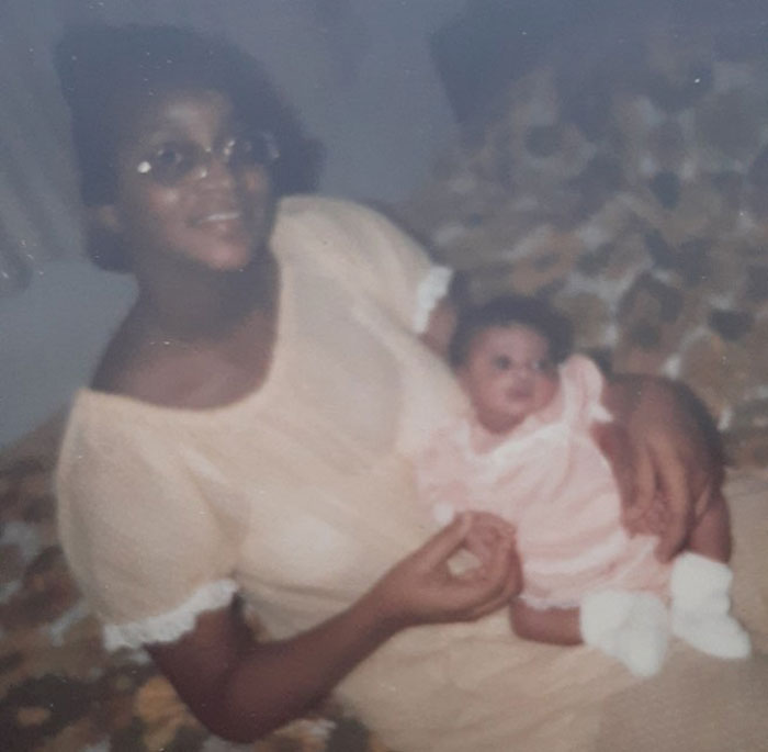 A woman in glasses holding a baby on a bed, related to Zendaya's family rift news.