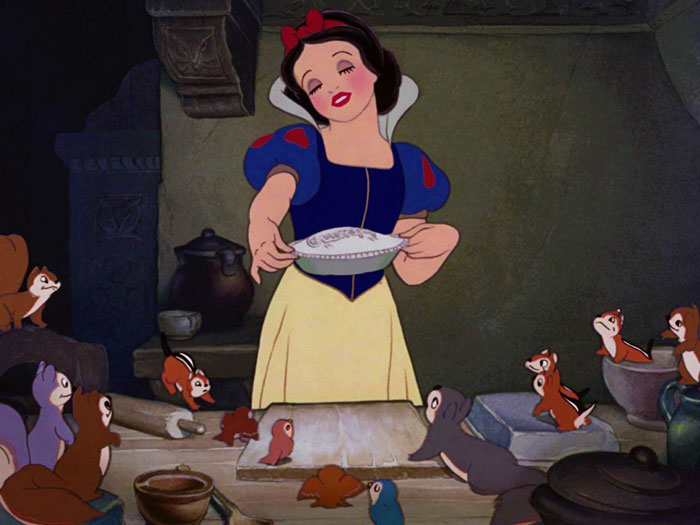 Snow White holding pie in a kitchen, surrounded by forest animals, illustrating changes in the new remake.