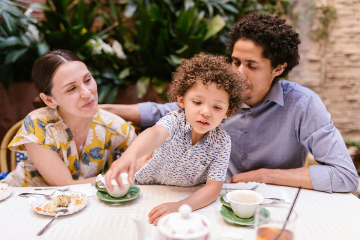 A family enjoying a meal at a pizza place, highlighting the atmosphere affected by unruly kids.