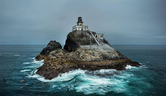 Lighthouse perched on a rocky island surrounded by crashing waves, exemplifying an iconic place in the world.