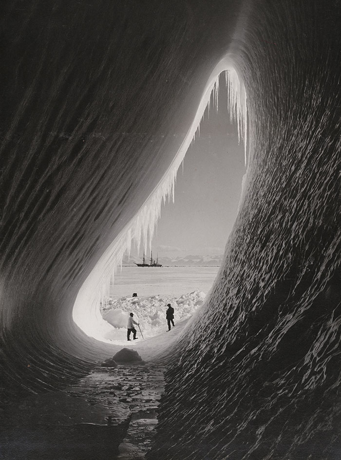 Ice cave with explorers in Antarctica, showcasing one of the world’s iconic places.