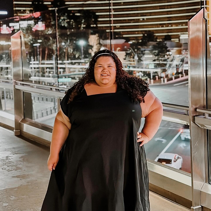 Plus-size woman stands confidently outdoors, addressing flying costs controversy.