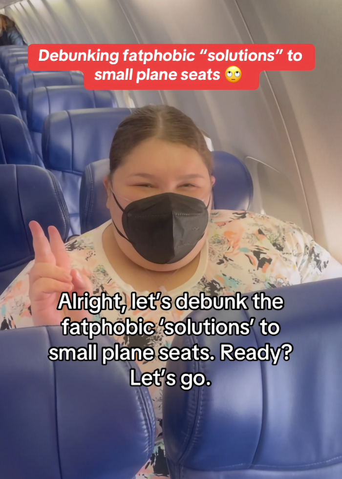 Plus-size woman in airplane seat, addressing criticism about paying extra to fly.