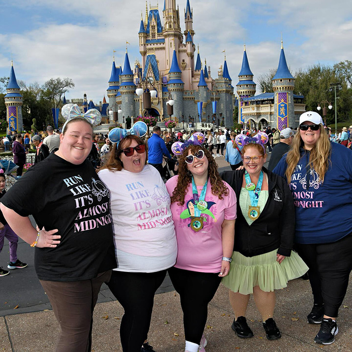 Plus-size park hoppers smiling in front of a castle, wearing themed shirts, showcasing empowerment. Plus-size park hoppers smiling in front of a castle, wearing themed shirts, showcasing empowerment.