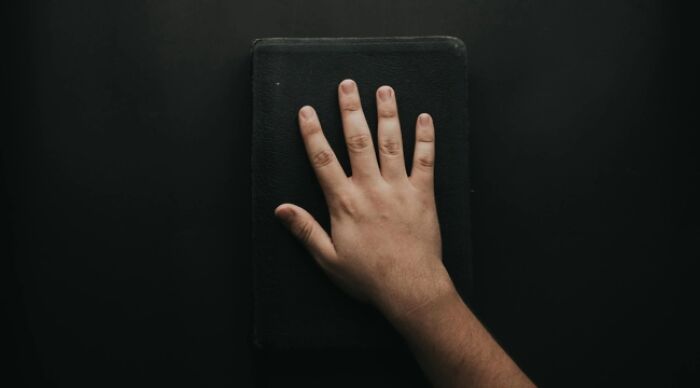 A hand placed on a closed black book, symbolizing a choice commitment.