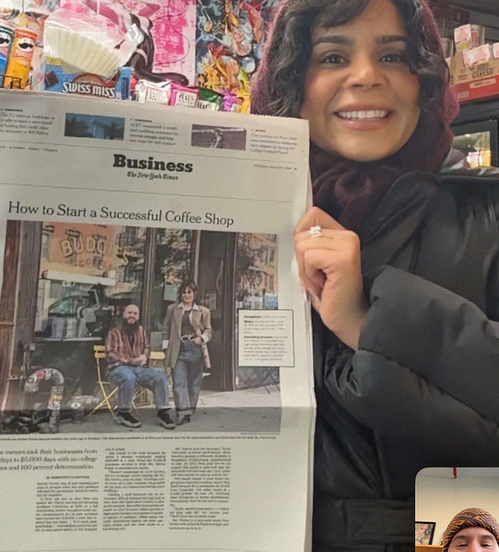 Smiling woman holds newspaper featuring NYC cafe success story article. Smiling woman holds newspaper featuring NYC cafe success story article.