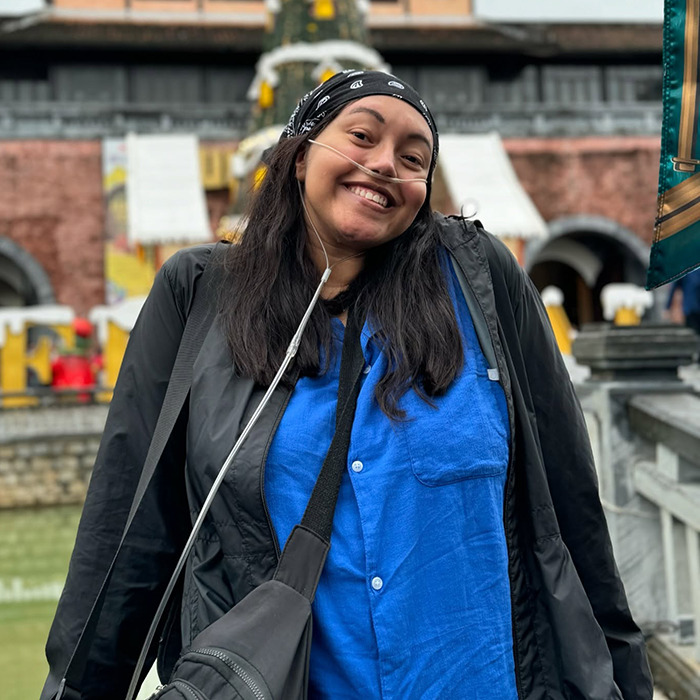 Stage 4 cancer patient Natasha Allen smiling outdoors wearing a blue shirt and a nasal cannula.
