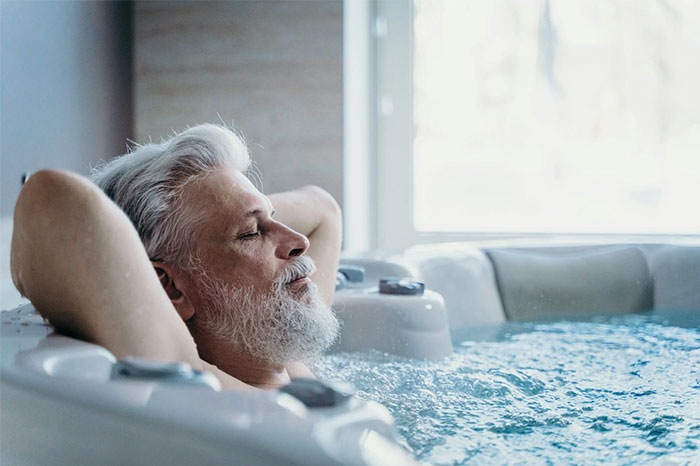 Man relaxing in a hot tub with eyes closed, showcasing a serene moment.