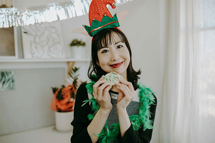 Woman in festive attire holding a decorated cookie, posing for a social media post.