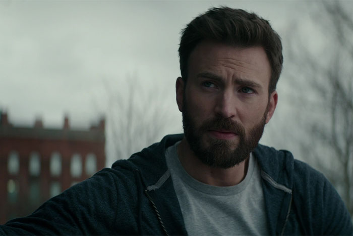 Man with a beard in a gray shirt and dark hoodie, outside on a cloudy day, related to social media mishaps.