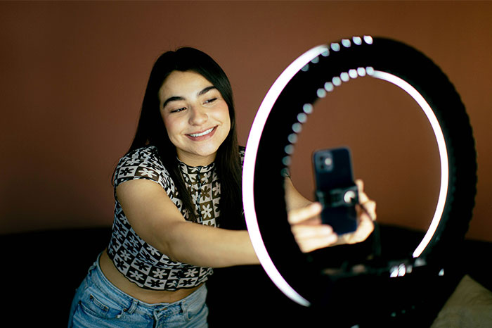 Woman taking a selfie with a ring light, capturing a moment for social media.