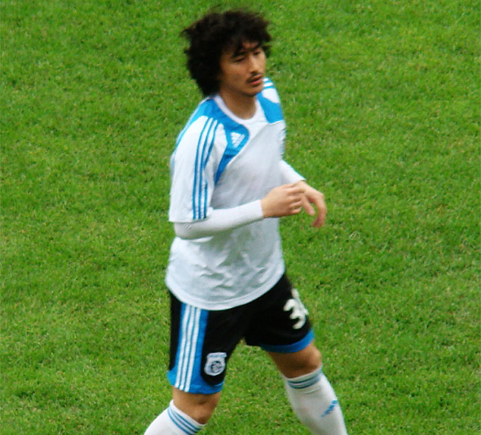 Soccer player in white and blue uniform on the field, representing fascinating sports facts.