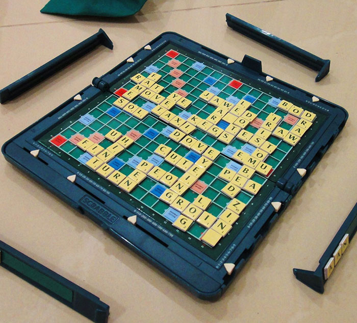 Scrabble board game in progress with various letter tiles arranged. Fun opportunity to learn something new.
