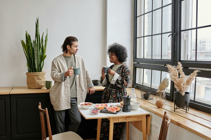 Man and woman enjoying coffee by a window, highlighting pretty privilege dynamics in social settings.