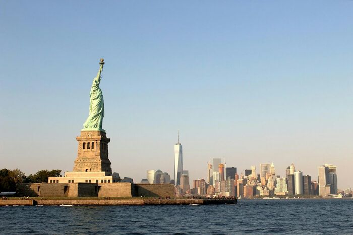 Statue of Liberty with New York City skyline; iconic American landmarks in clear weather.