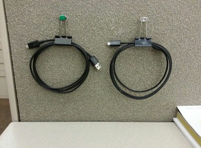 Binder clips used as cable organizers, showing creative product use in a cubicle setting.