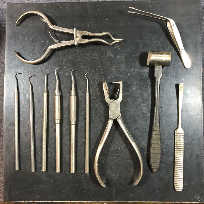 Various metal tools displayed on a dark surface, used for different purposes than originally intended.