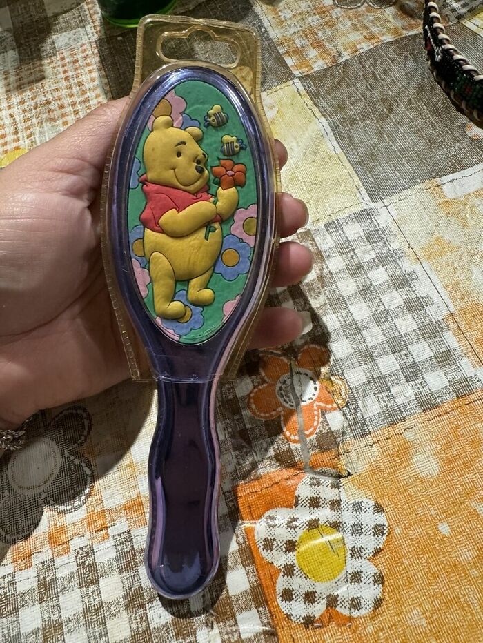 Winnie the Pooh hairbrush held in hand, featuring playful design, possibly used for a different purpose.