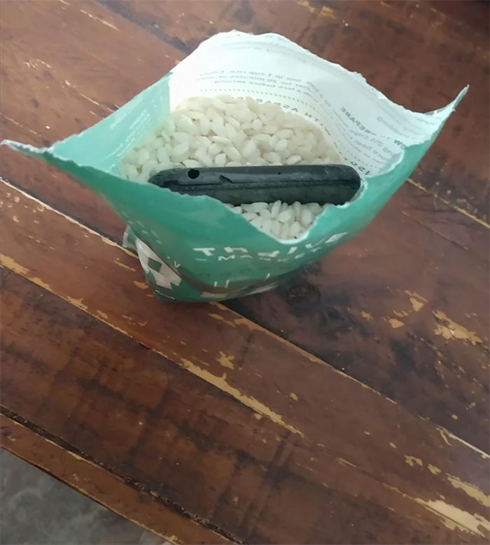 Phone in a rice bag used for drying purpose on a wooden table.
