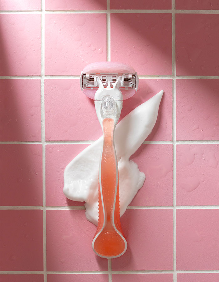 Razor with shaving cream on pink tiles, symbolizing the cultural moment and debate over pubic hair.