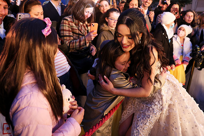 Snow White event in Spain; a woman in costume hugging a child amid a gathered crowd.