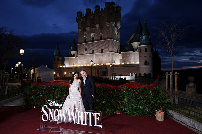 Snow White event with castle backdrop, featuring two people standing by a Disney sign at night in Spain.