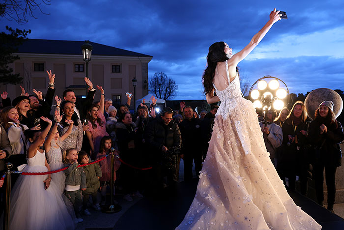 Person in a gown taking a selfie at a small Snow White-themed event outside, surrounded by a small group.