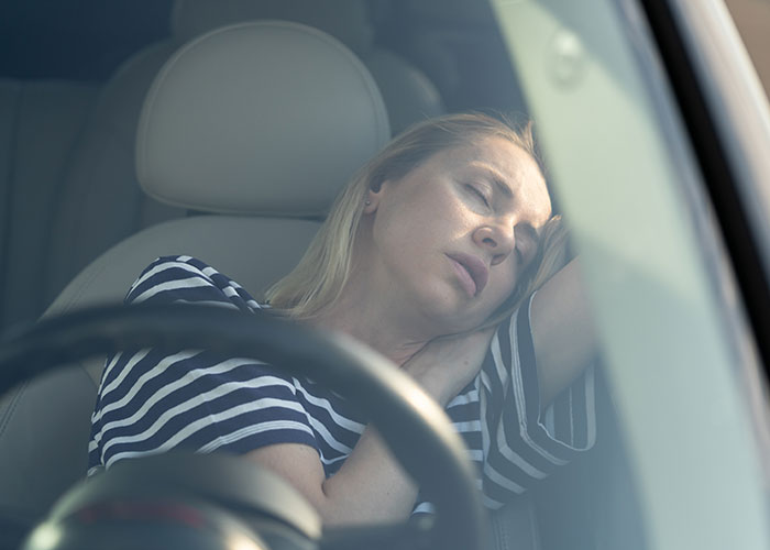 Woman in striped shirt asleep in car, illustrating feelings of neglect in friendships.