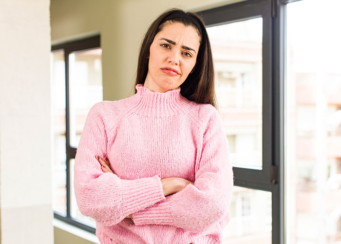 Person in a pink sweater with crossed arms, conveying discontent, related to friendship care insights.