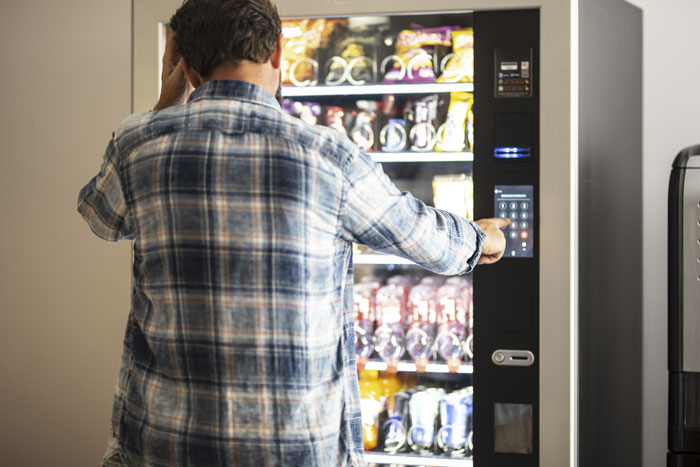 Man in a plaid shirt using a vending machine, reflecting themes of free rides and lending money.