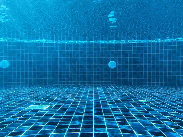 Blue tiled swimming pool underwater view, highlighting homeowner's excitement and unexpected visitor scenario.